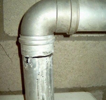 Een aluminium bocht van een rookgasafvoer met een doorgevreten naad, vier jaar na de plaatsing